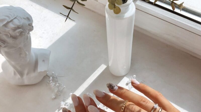 a woman's hands on a table with a vase of flowers